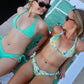 Two women in bikinis posing on a towel outdoors